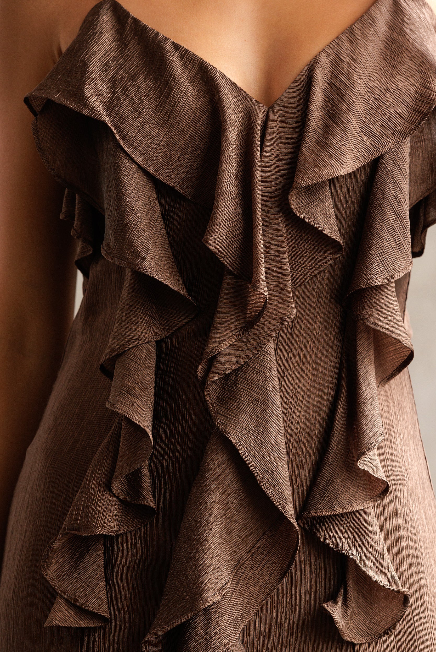 Brown ruffled fabric draped over a mannequin against a neutral background