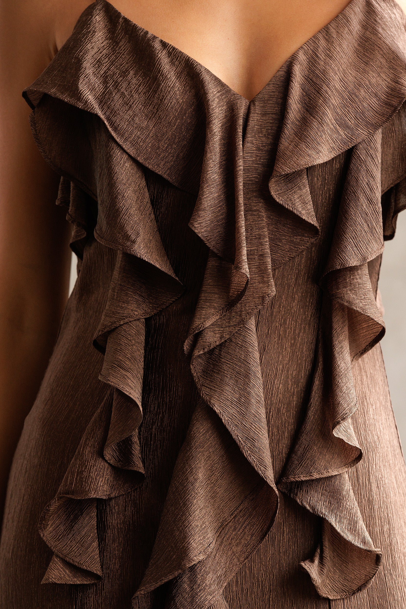 Brown ruffled fabric draped over a mannequin against a neutral background
