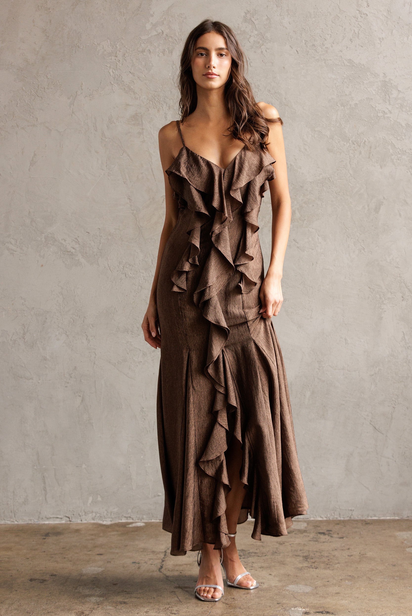 Woman wearing a brown ruffled dress against a plain background