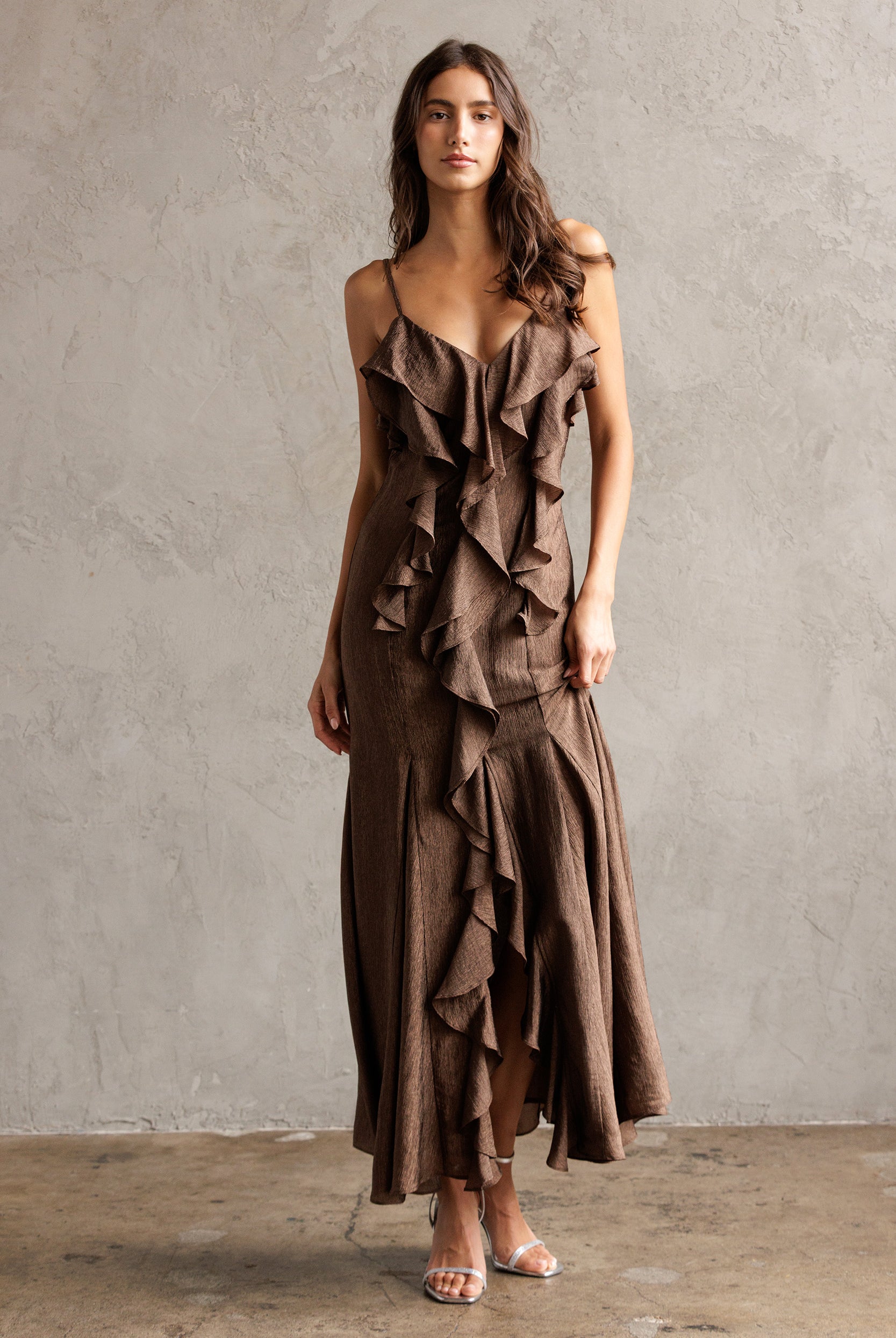 Woman wearing a brown ruffled dress against a plain background