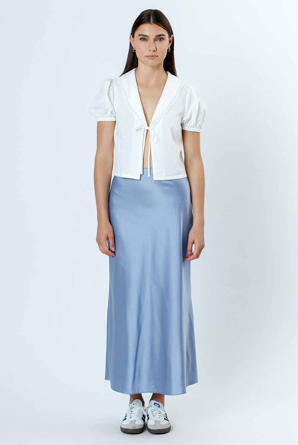 Woman wearing a white blouse and light blue skirt on a white background