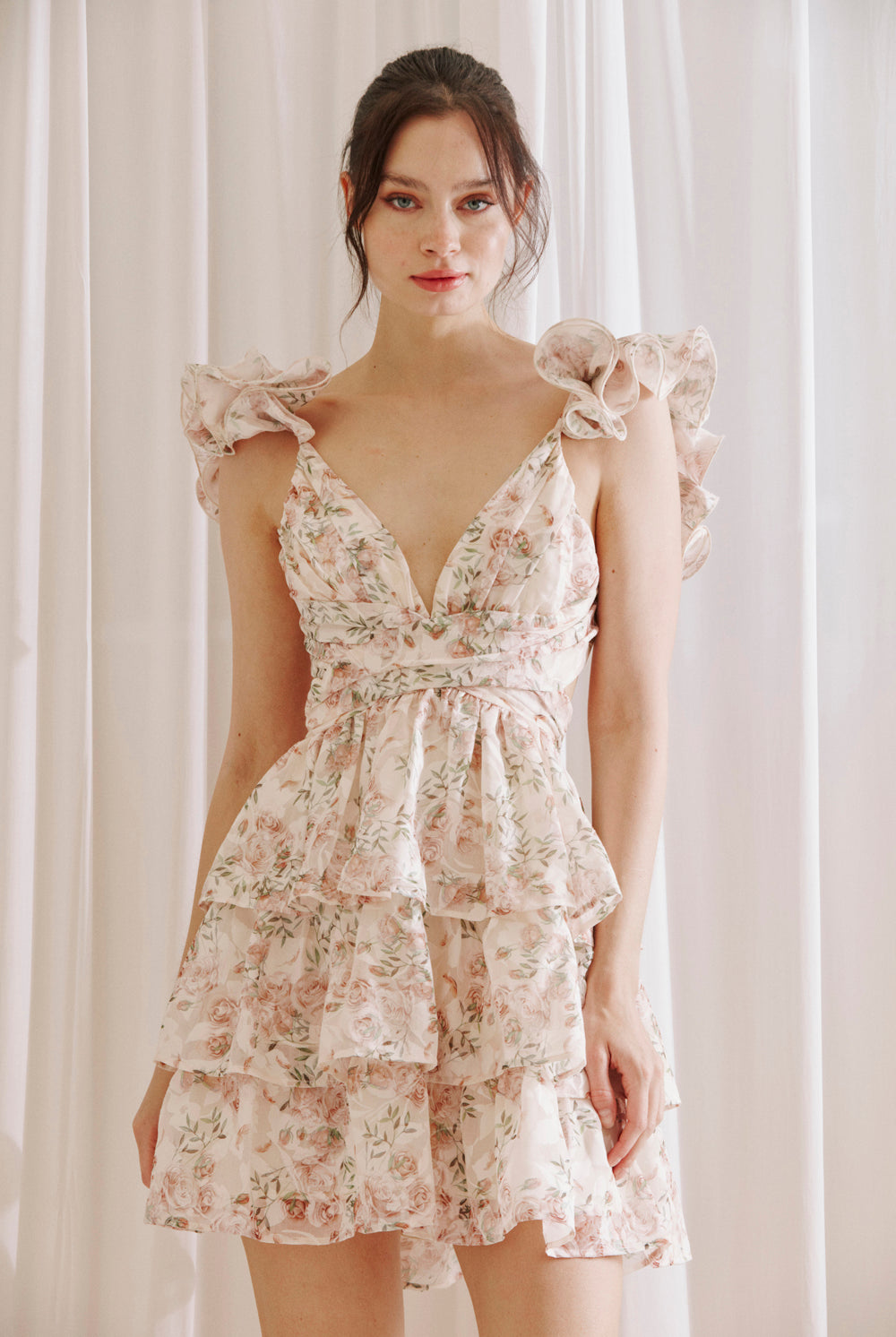 Blush floral ruffle mini dress with V-neckline, flutter sleeves, and tiered skirt