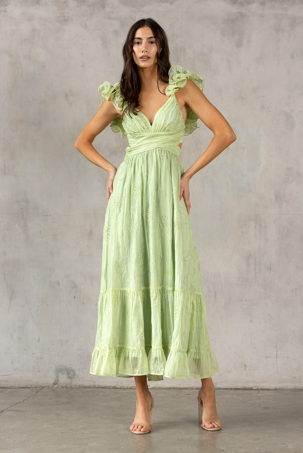 Woman wearing a lme green dress against a gray concrete wall