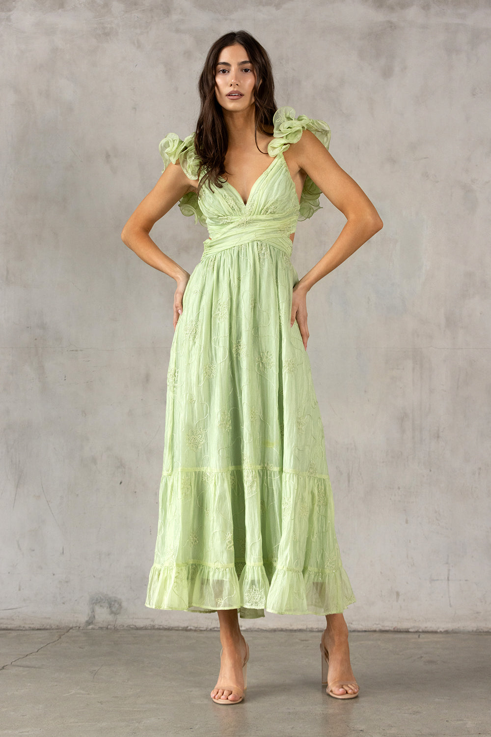 Woman wearing a lme green dress against a gray concrete wall