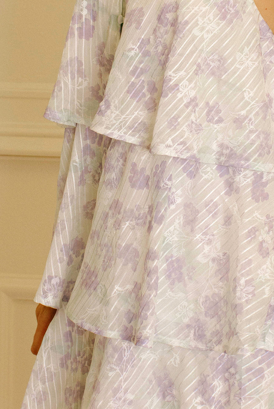 Lavender slip dress with floral and stripe pattern against a beige wall