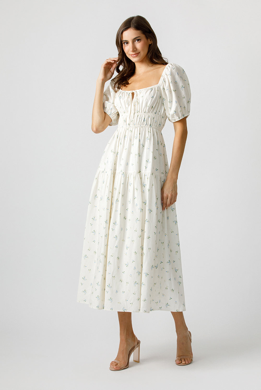 Woman wearing a cream floral dress on a plain background