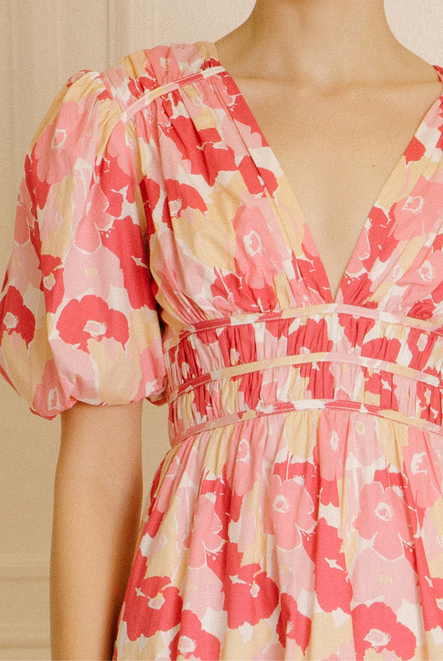 Pink and beige dress with a big floral pattern against a beige wall