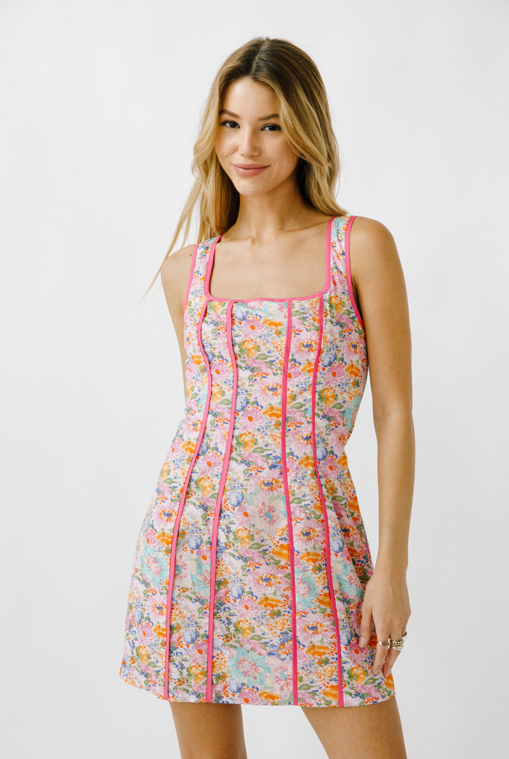 Woman wearing a floral dress with pink trim on a white background
