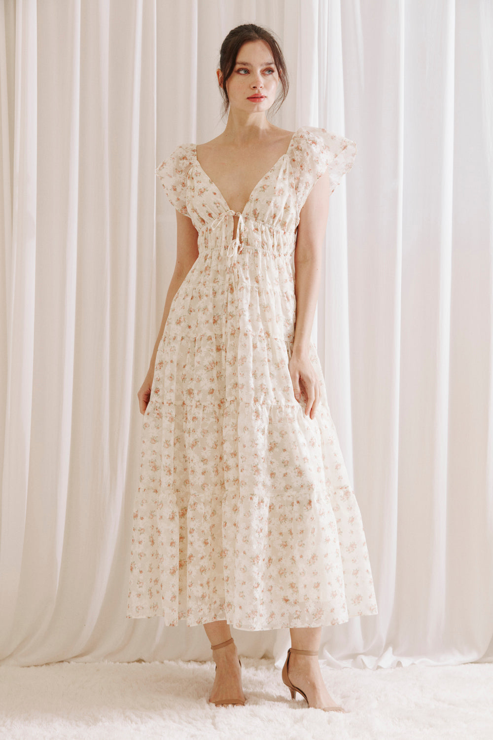 Woman wearing a floral dress against a white curtain background