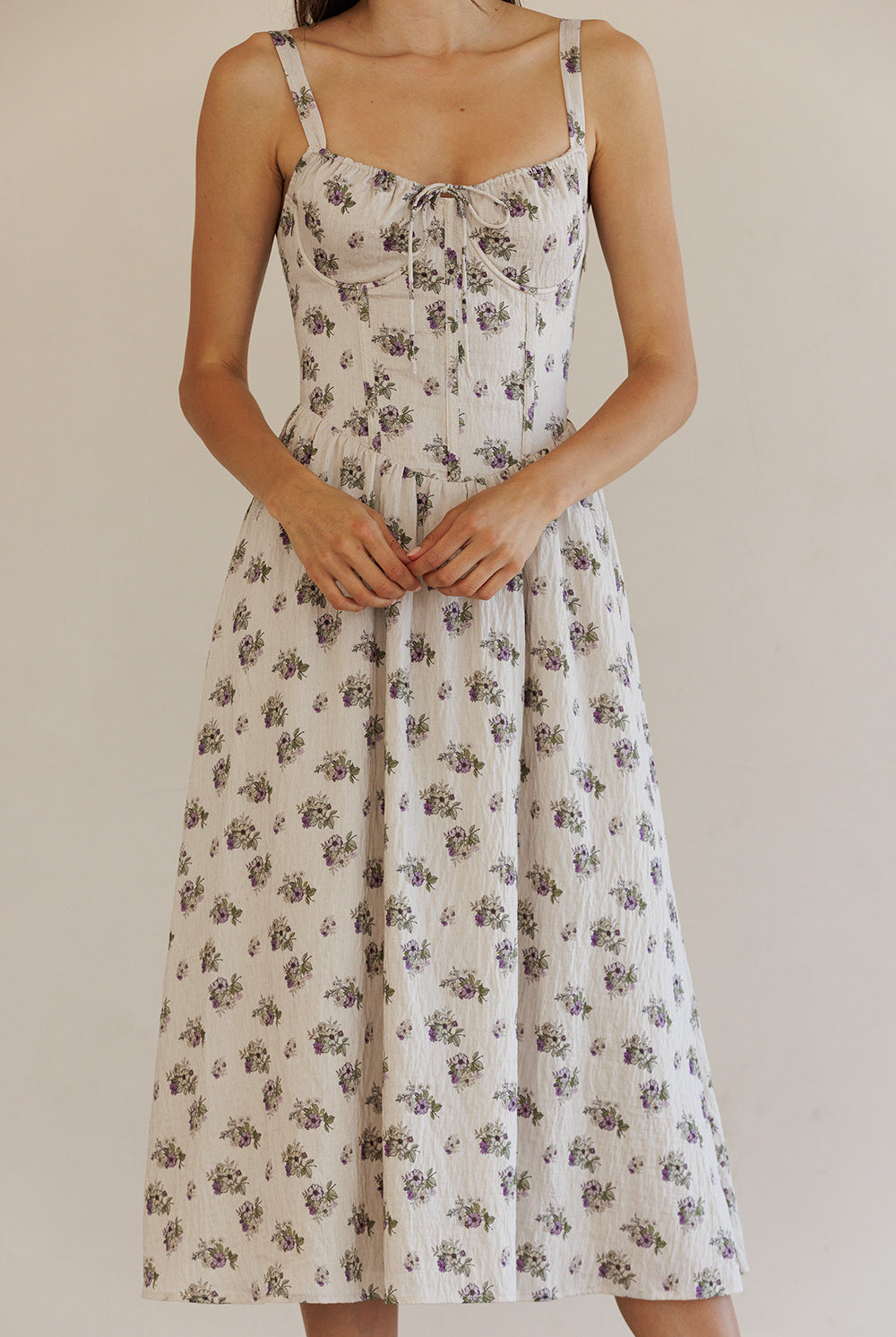 Woman wearing a beige floral dress against a plain background