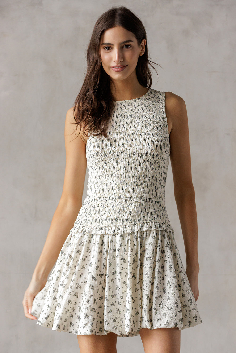 Woman wearing an ivory floral dress against a gray background
