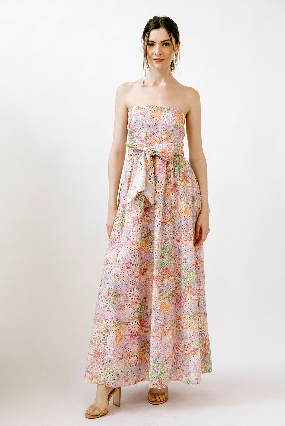 Woman wearing a colorful floral print on embroidered eyelet fabric strapless dress on a white background