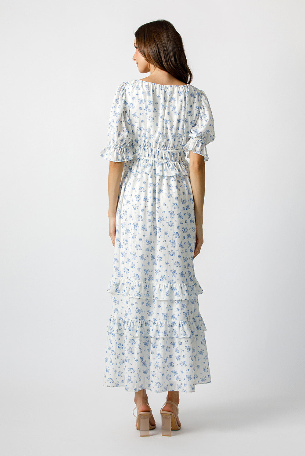 Woman wearing a blue floral pattern maxi dress on a white background
