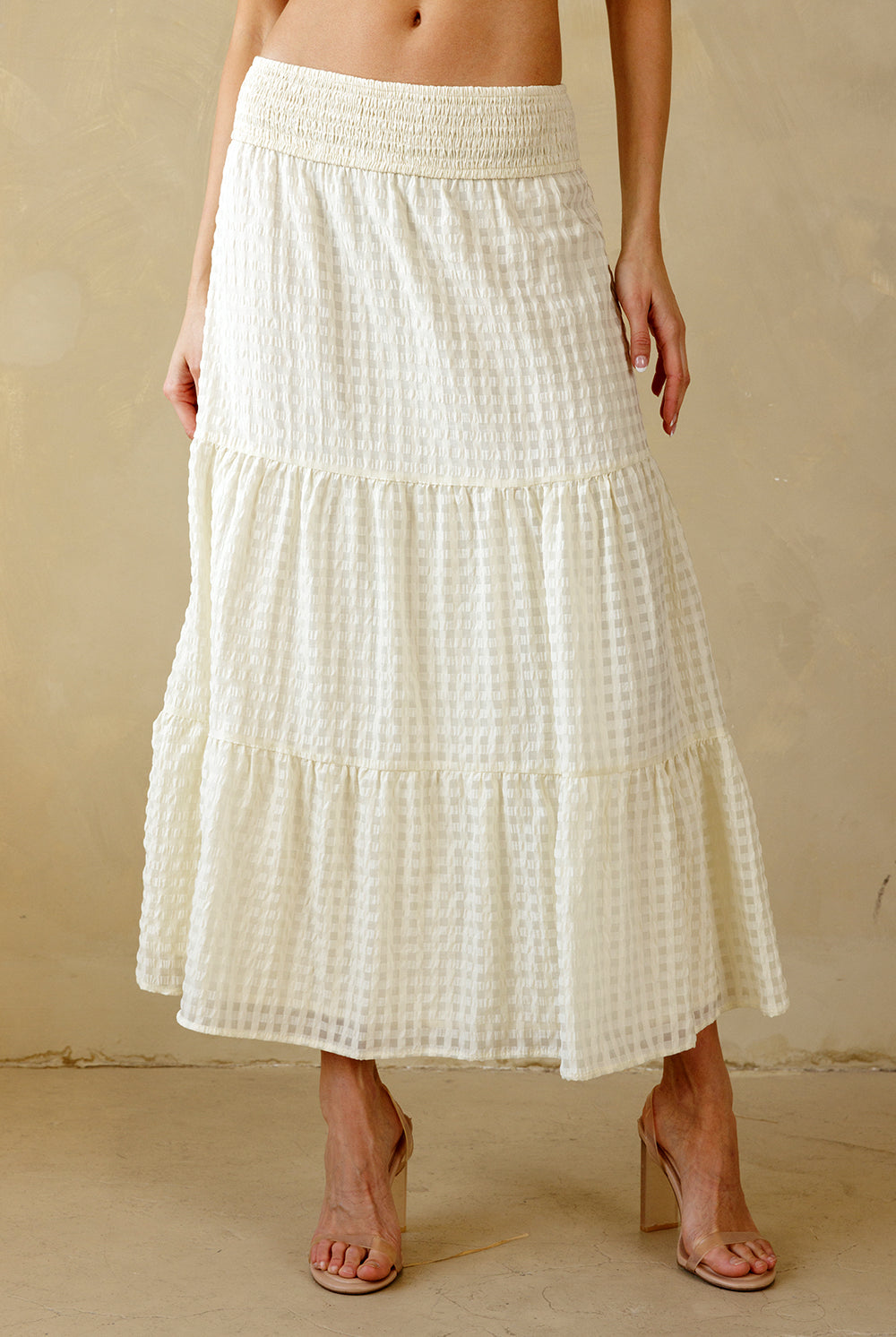 Cream maxi skirt with a subtle checkered pattern worn by a person on a beige background