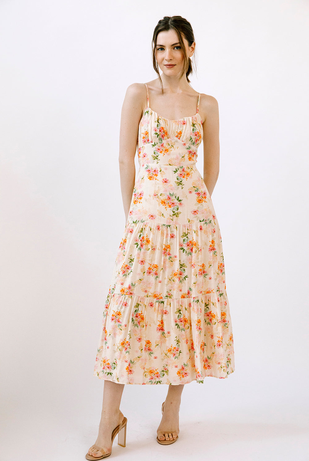 Woman wearing a cream dress with a watercolor-inspired floral pattern on a white background