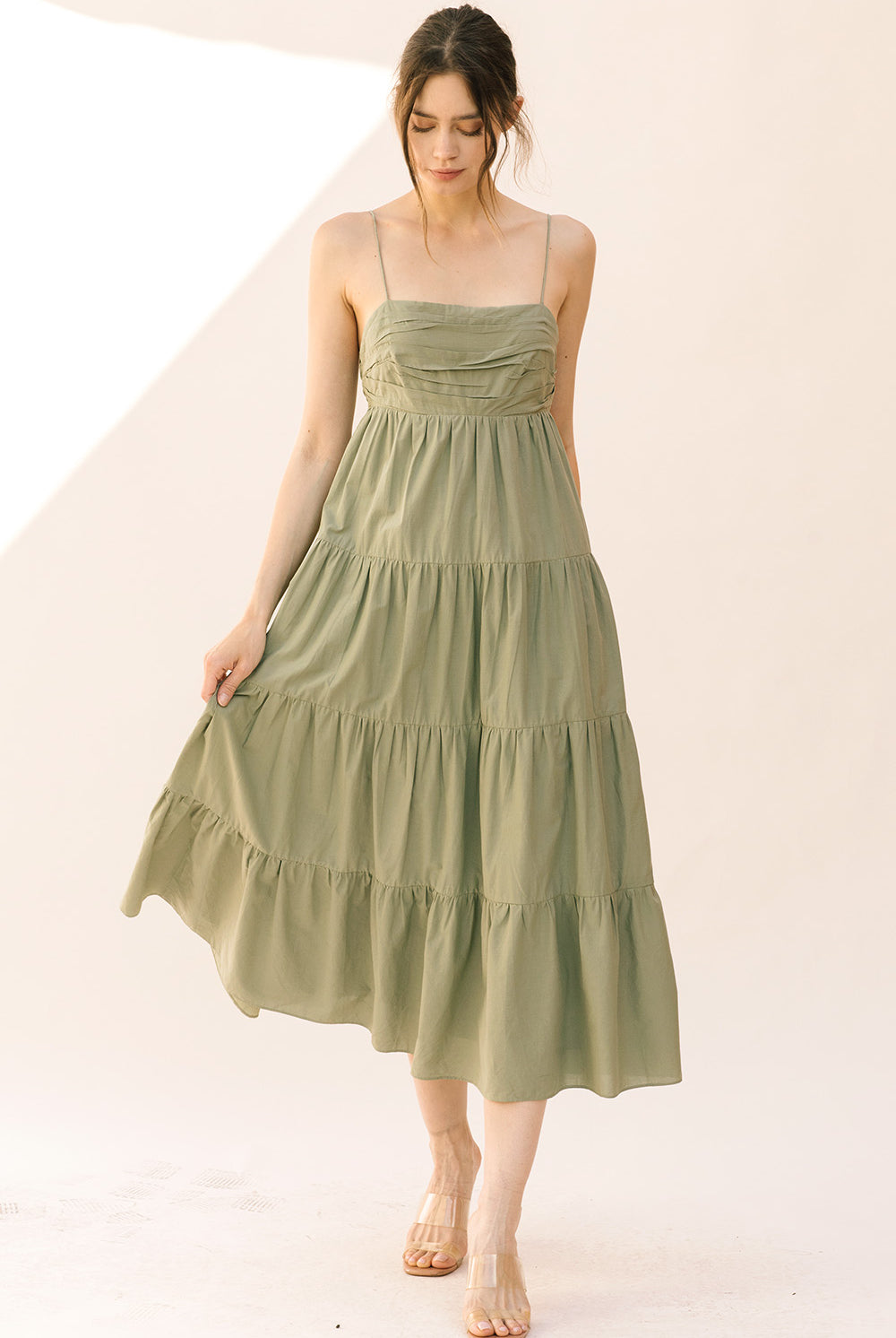 Woman wearing a green tiered dress on a white background