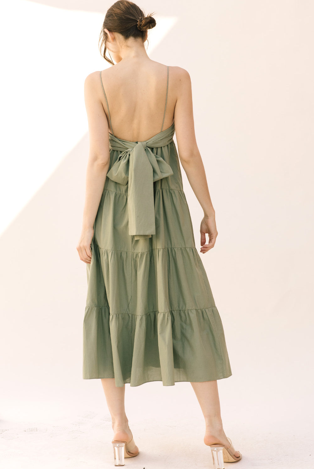 Woman wearing a green dress with a bow detail on a white background