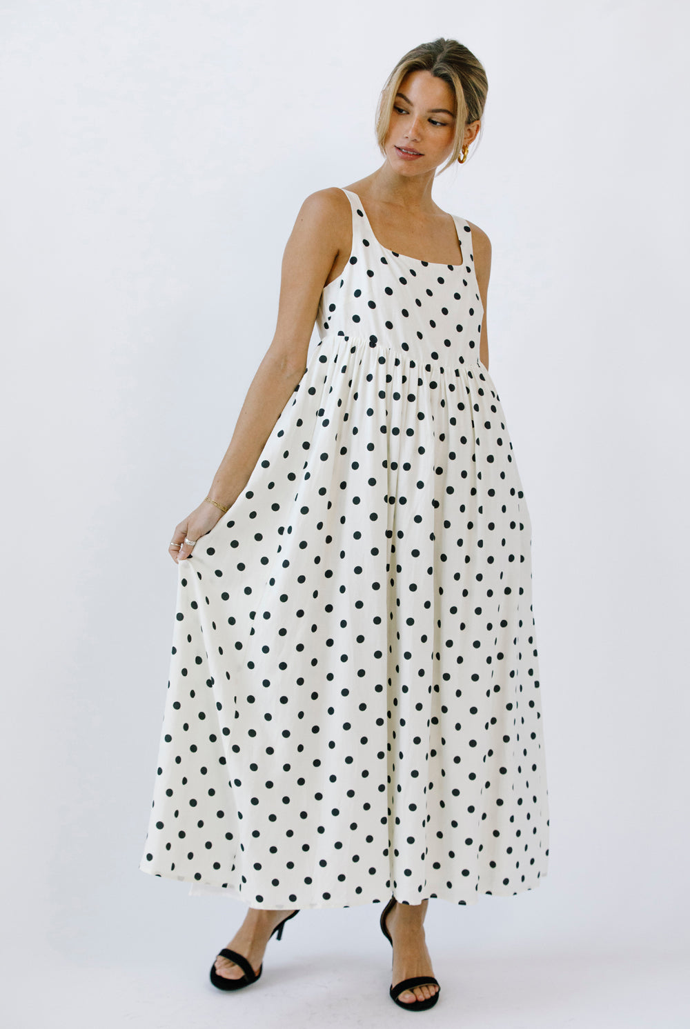 Woman wearing a polka dot dress and black high-heels on a white background