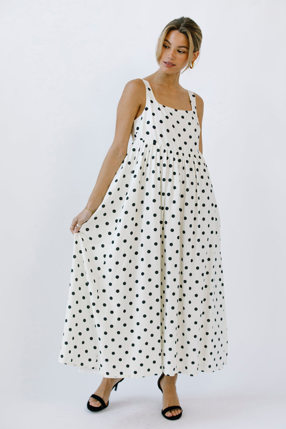 Woman wearing a polka dot dress and black high-heels on a white background