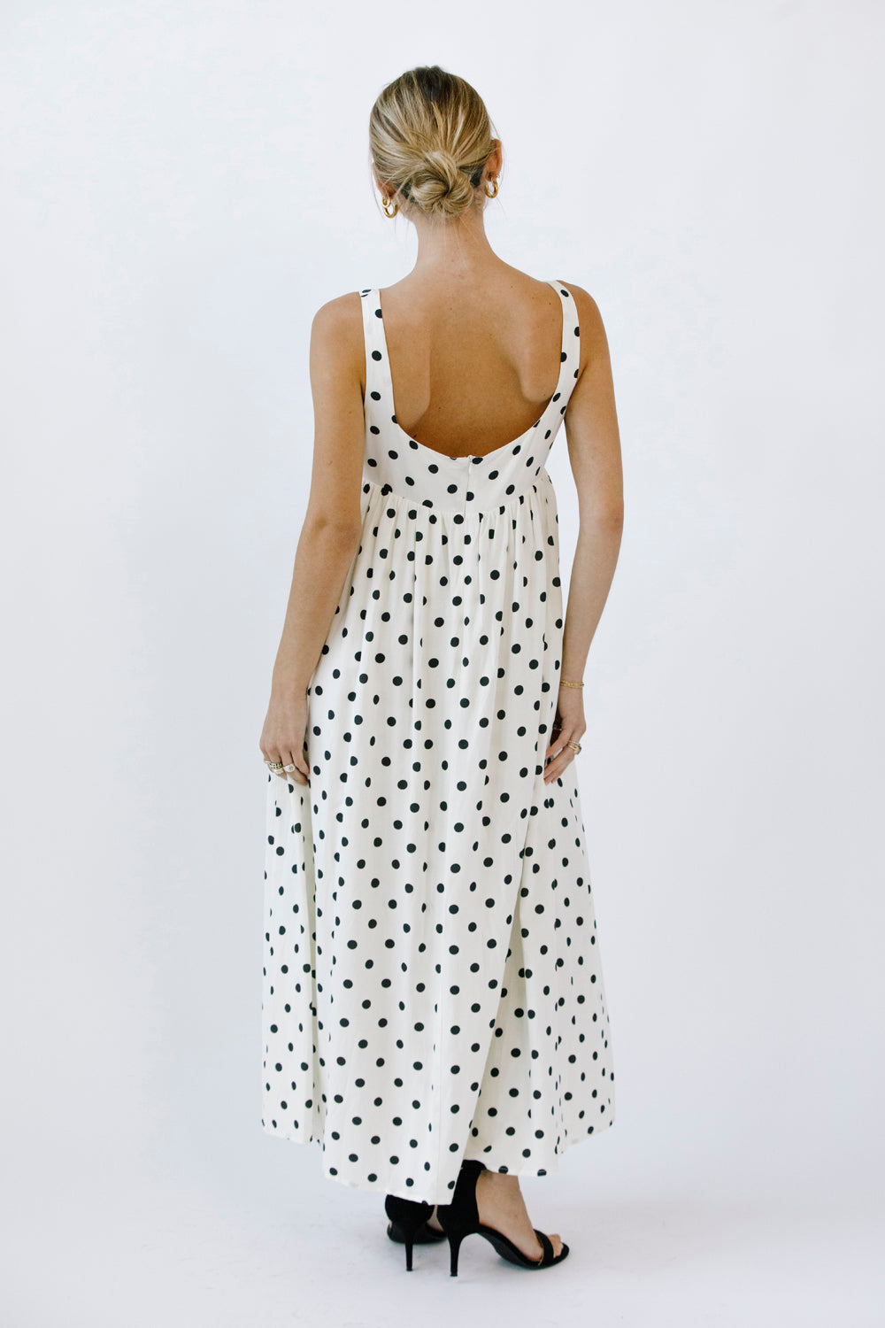 Back view of a woman wearing a polka dot dress on a white background