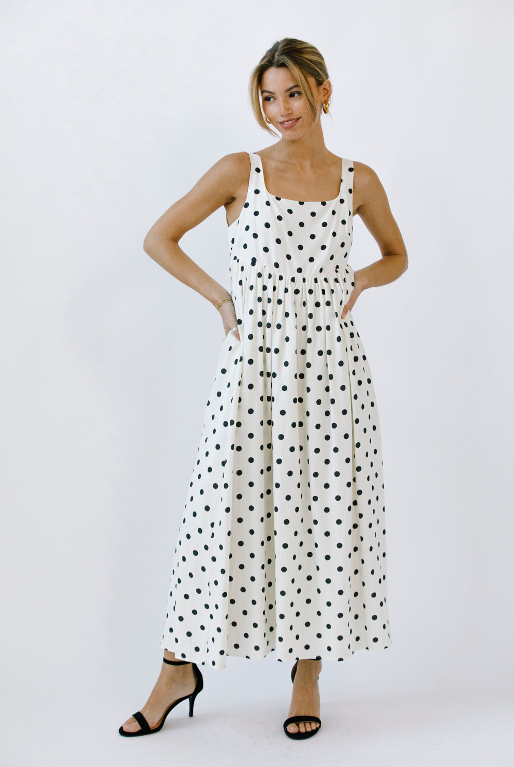 Woman wearing a polka dot maxi dress on a white background
