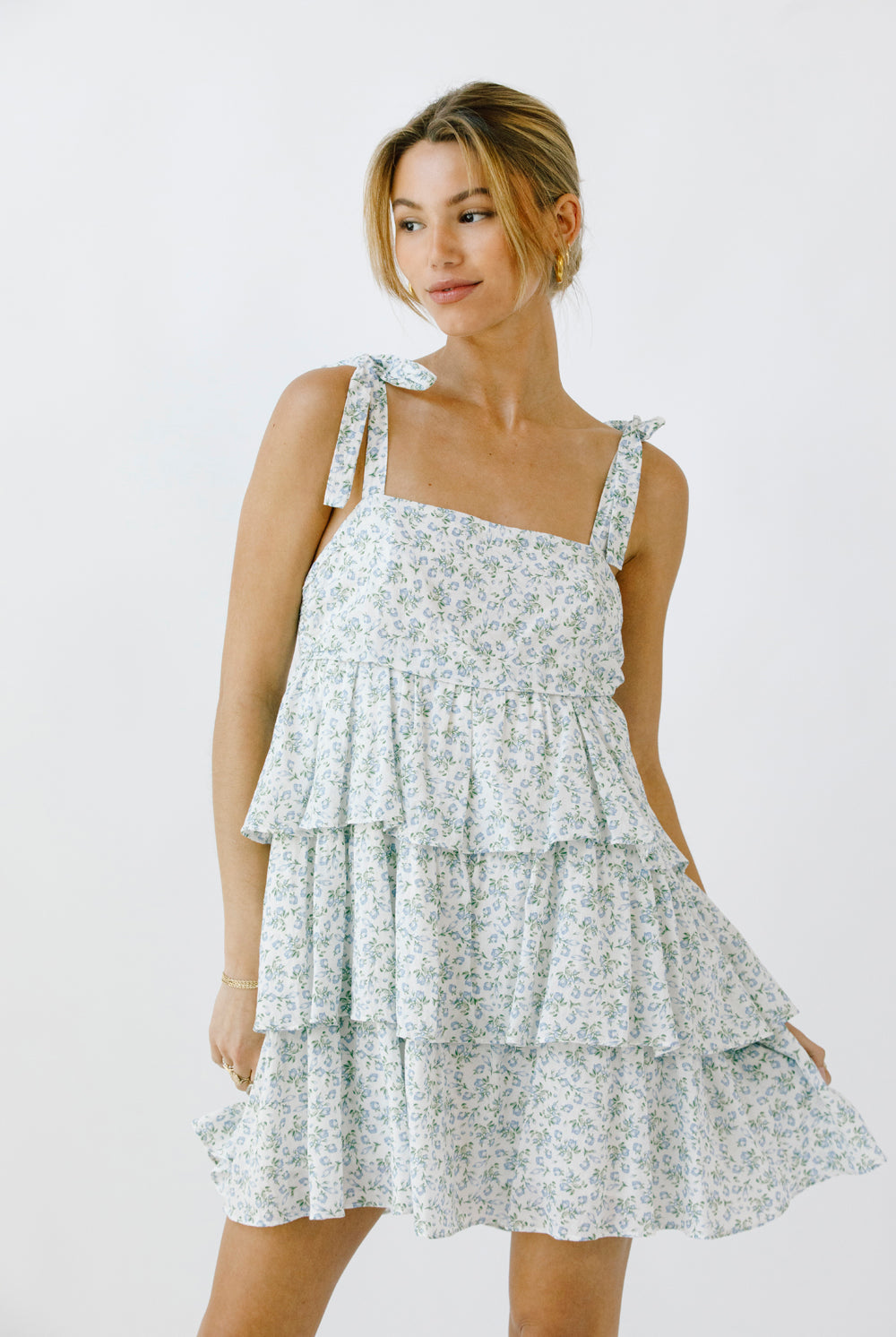 Woman wearing a floral dress with a tiered ruffle design on a white background
