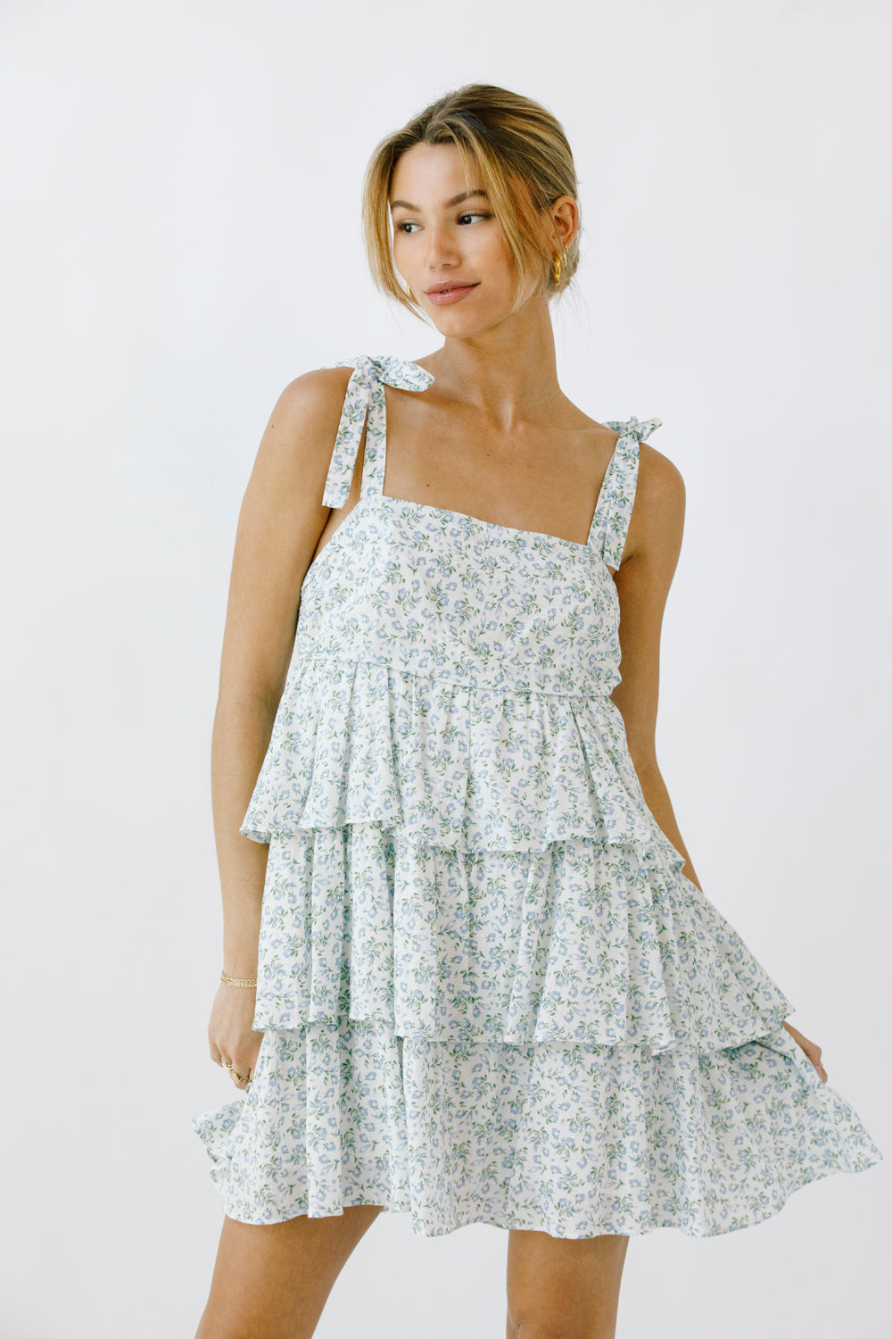 Woman wearing a floral dress with a tiered ruffle design on a white background