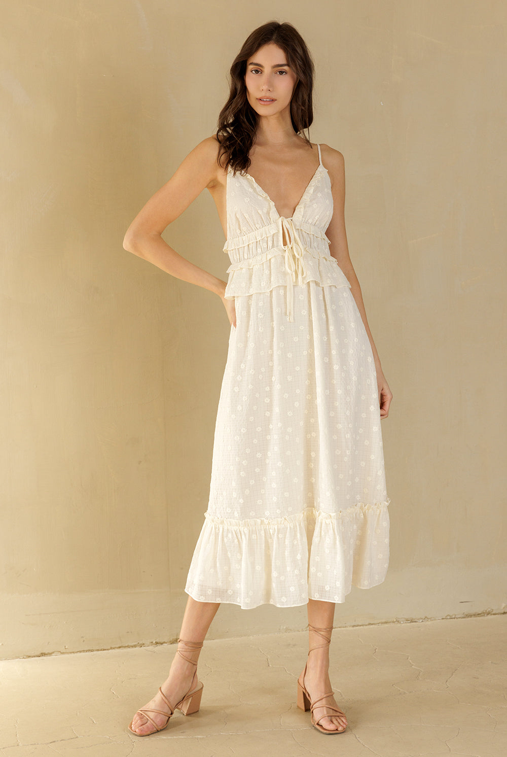 Woman wearing a cream midi dress against a beige background