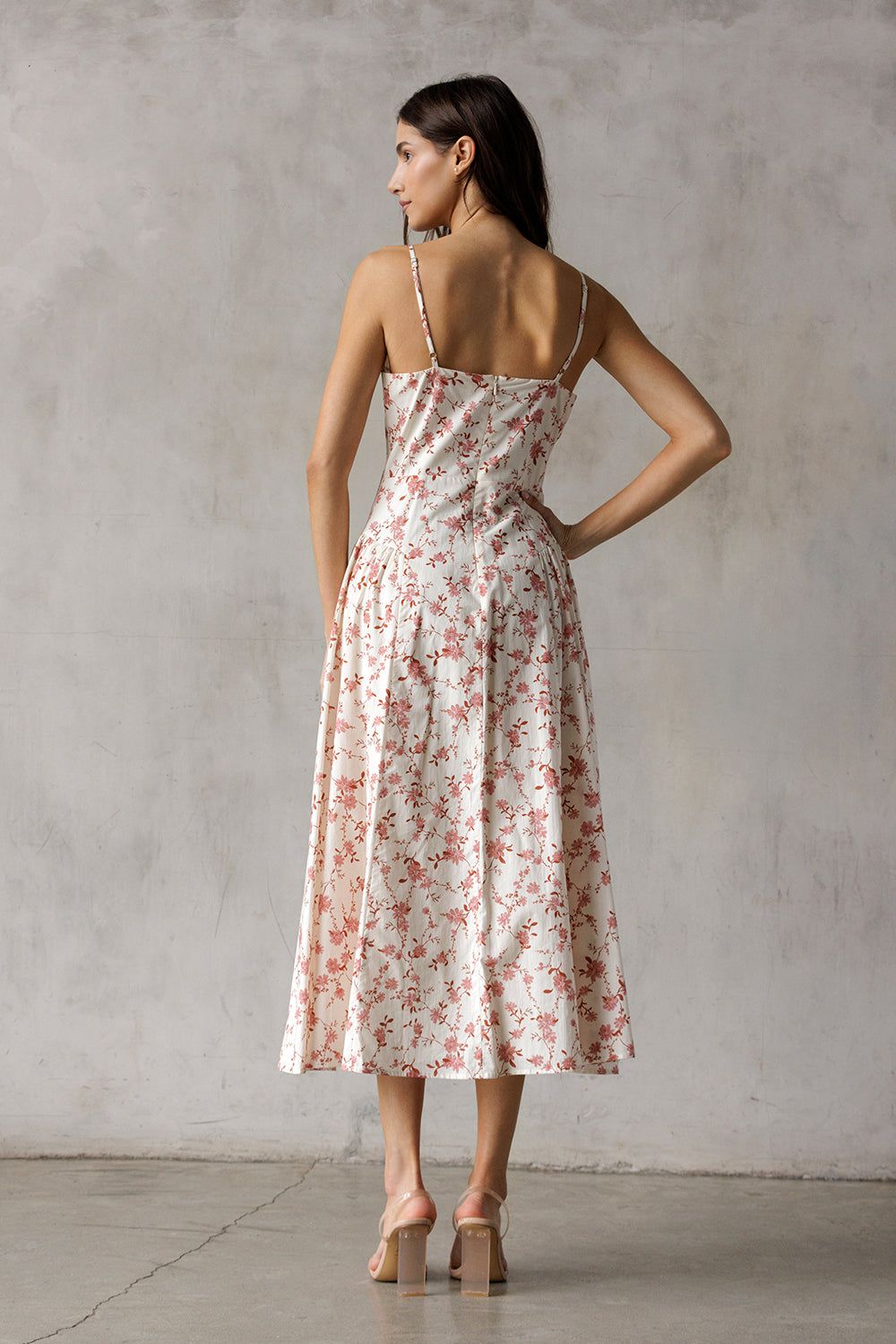 Woman wearing a cream and mauve floral dress against a plain background