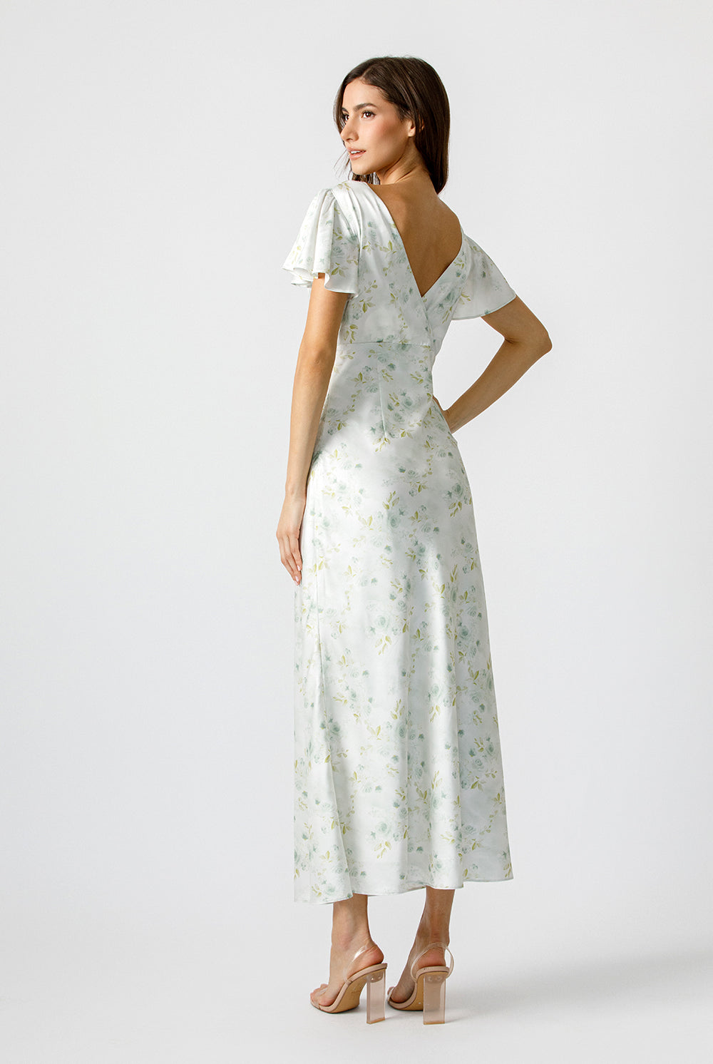 Back view of a woman wearing a soft pastel floral print maxi dress and fluttery short sleeves.