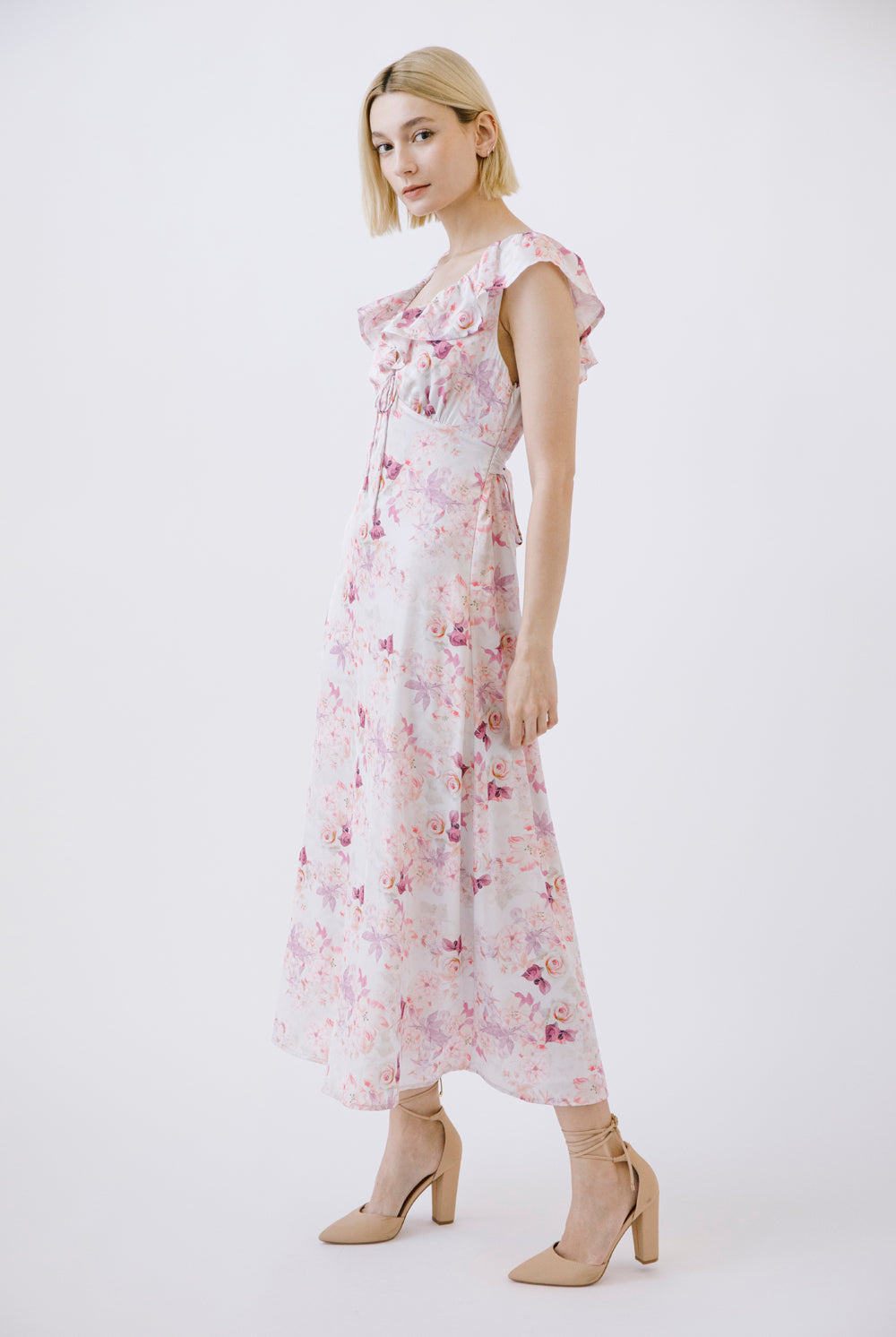 Woman wearing a floral dress and beige heels on a white background