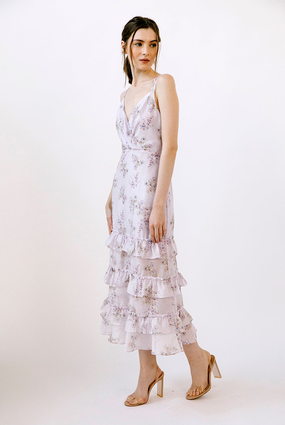 Side view of a woman wearing a lilac floral midi dress on a white background