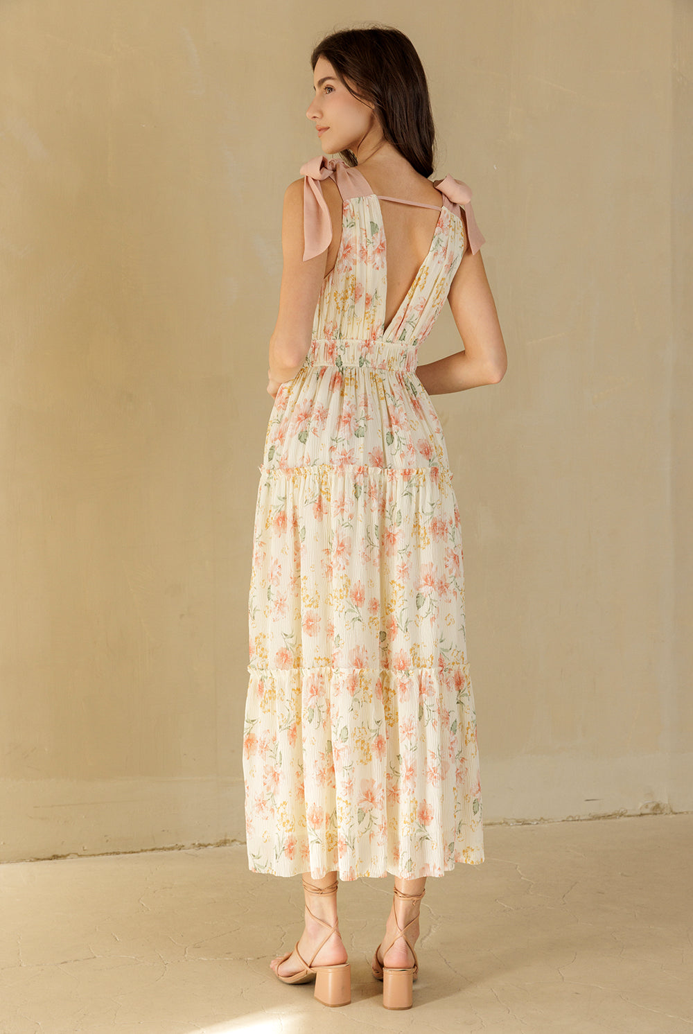 Woman wearing a cream floral dress against a beige background