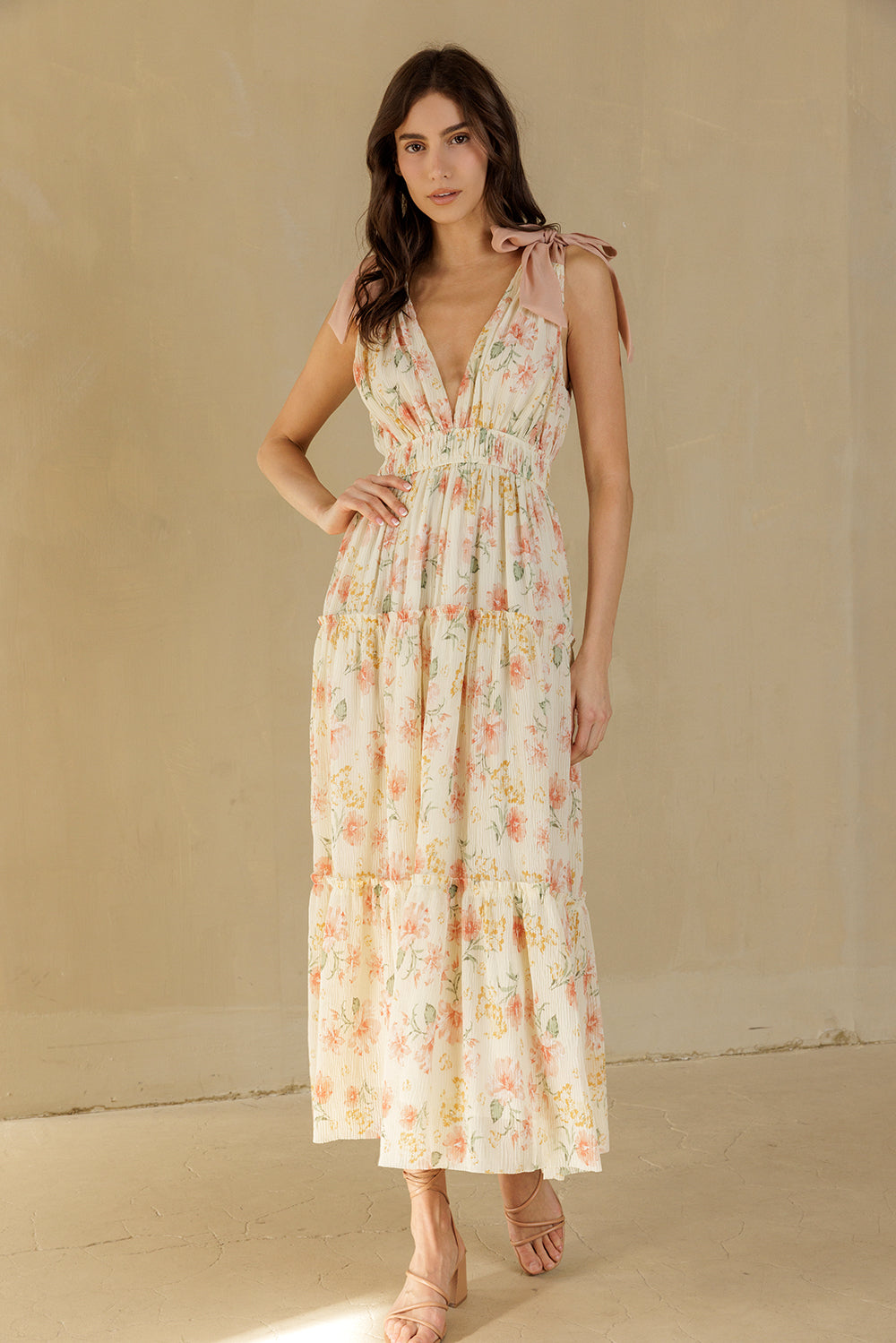 Woman wearing a cream floral dress against a beige background