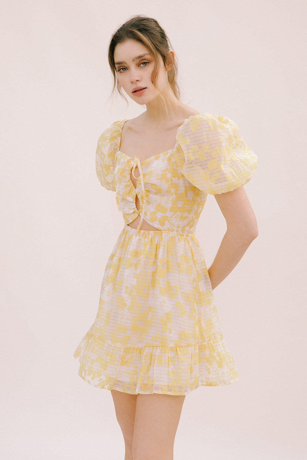 Woman wearing a yellow floral dress on a light pink background