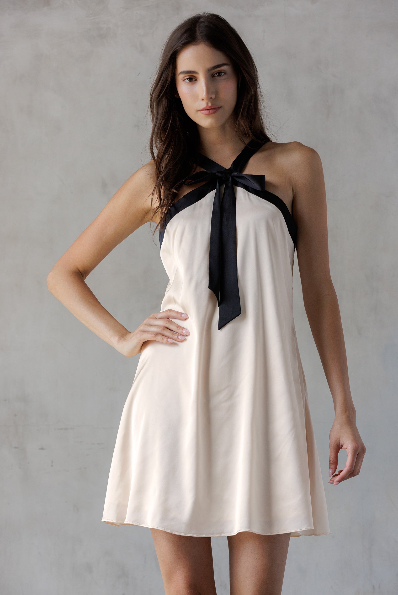 Woman wearing a white dress with a black ribbon on a gray background