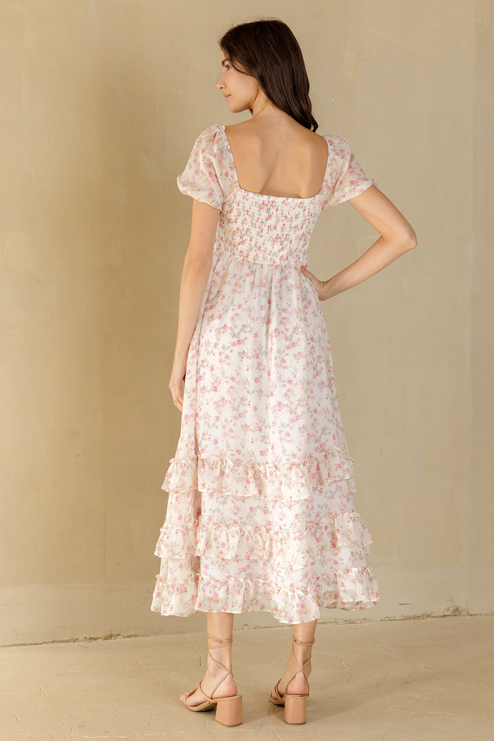 Woman wearing a white and pink floral dress against a beige background