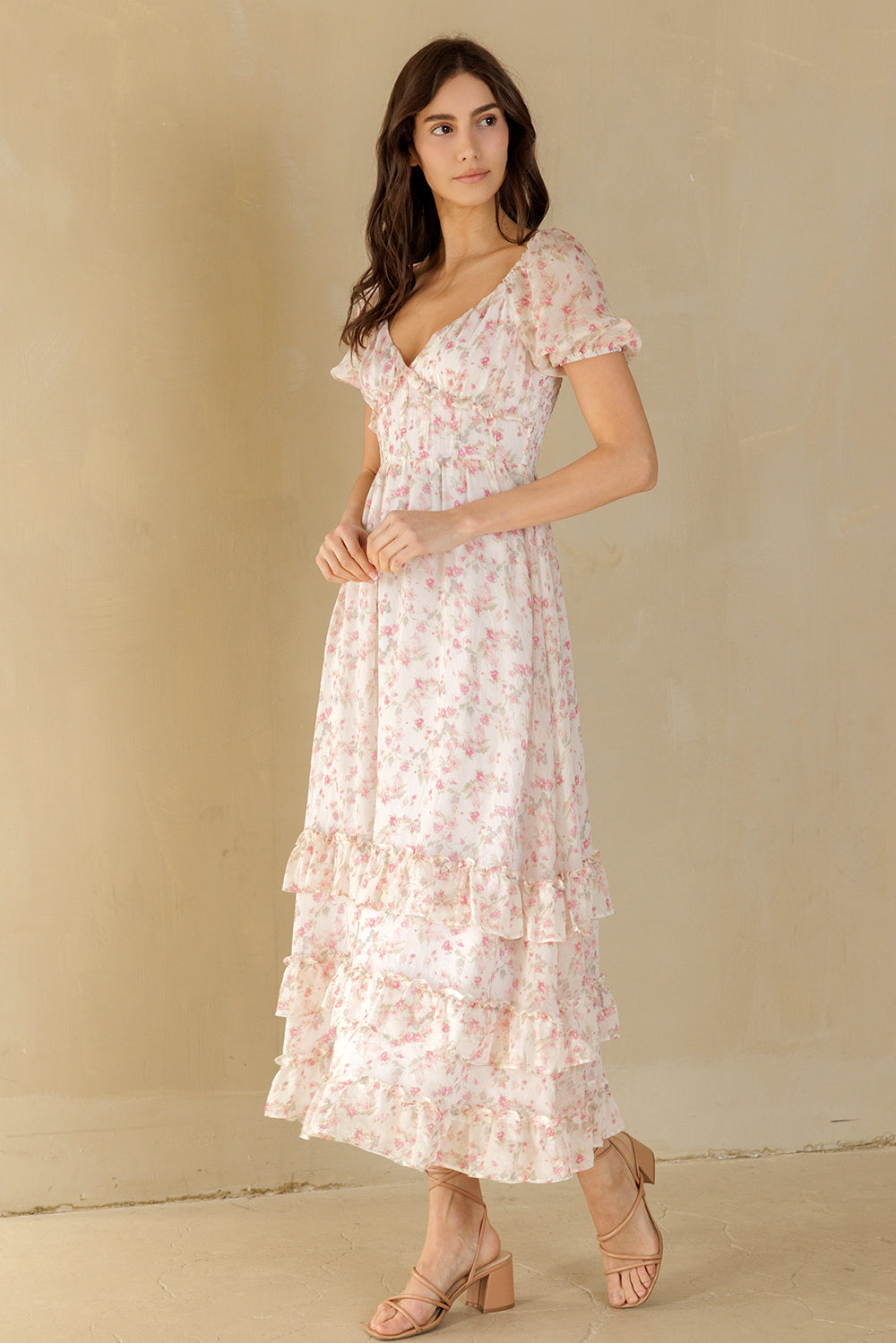 Woman wearing a white floral dress against a beige background