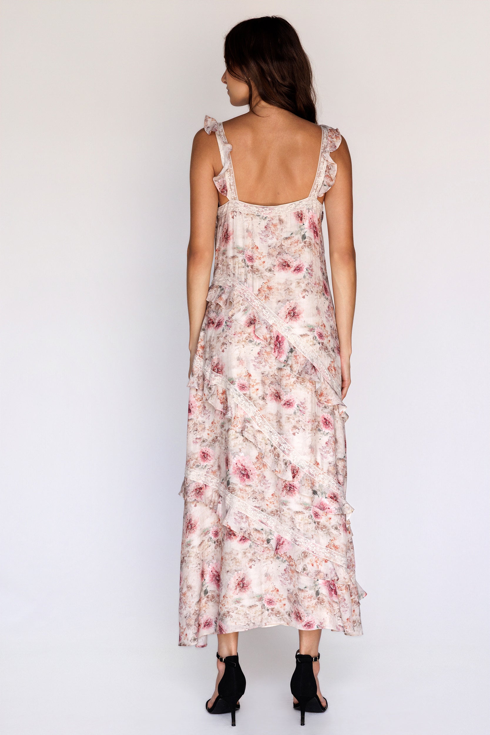 Back view of a woman wearing a floral dress on a white background