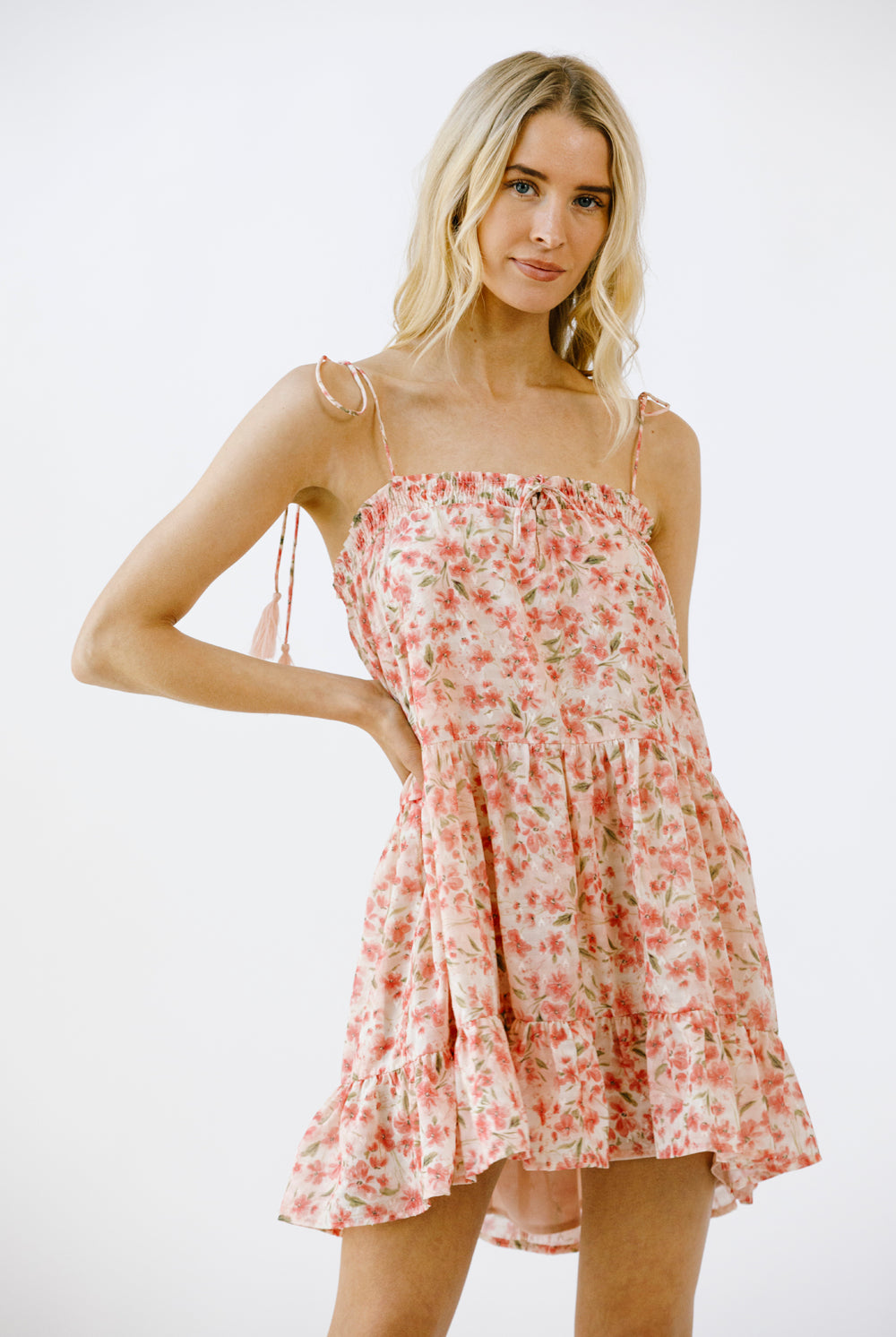 Woman wearing a vibrant pink floral print mini dress on a white background