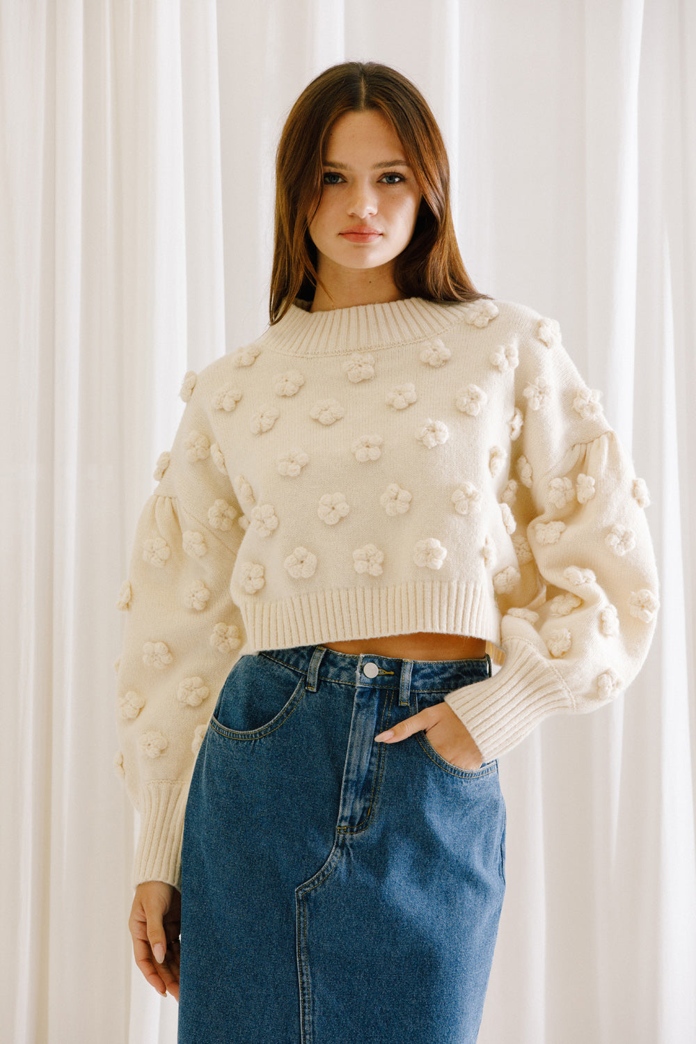 Woman wearing a cropped sweater in cream color