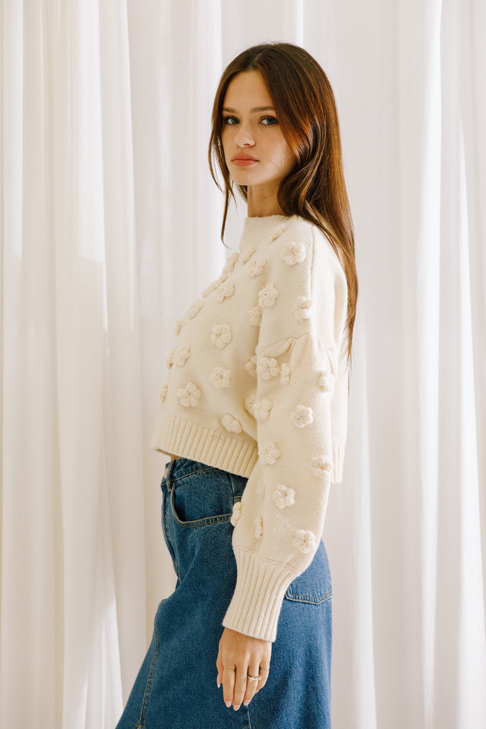 Woman wearing a cropped sweater with 3D daisy flowers
