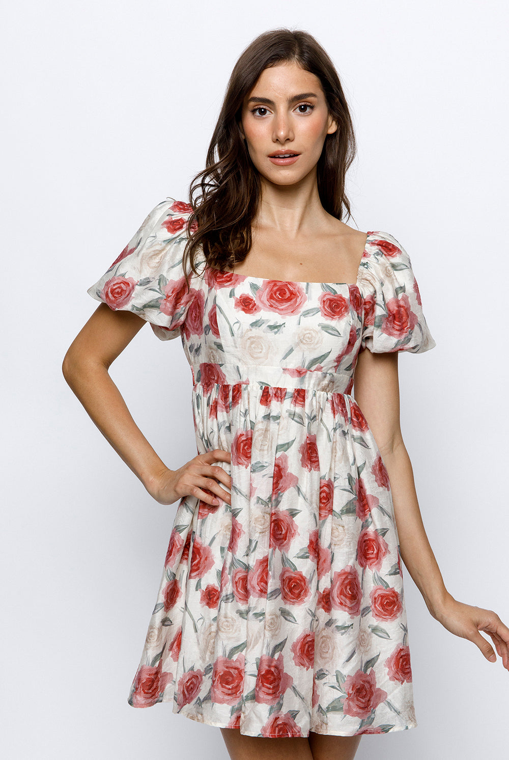 Woman wearing an ivory dress with red roses pattern on a white background