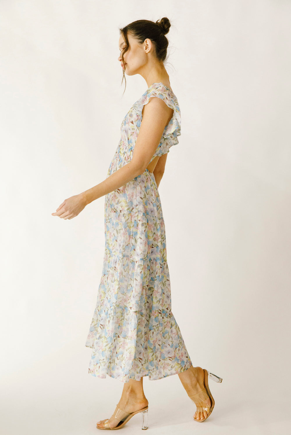 Side view of a woman wearing a blue and pink floral dress on a white background