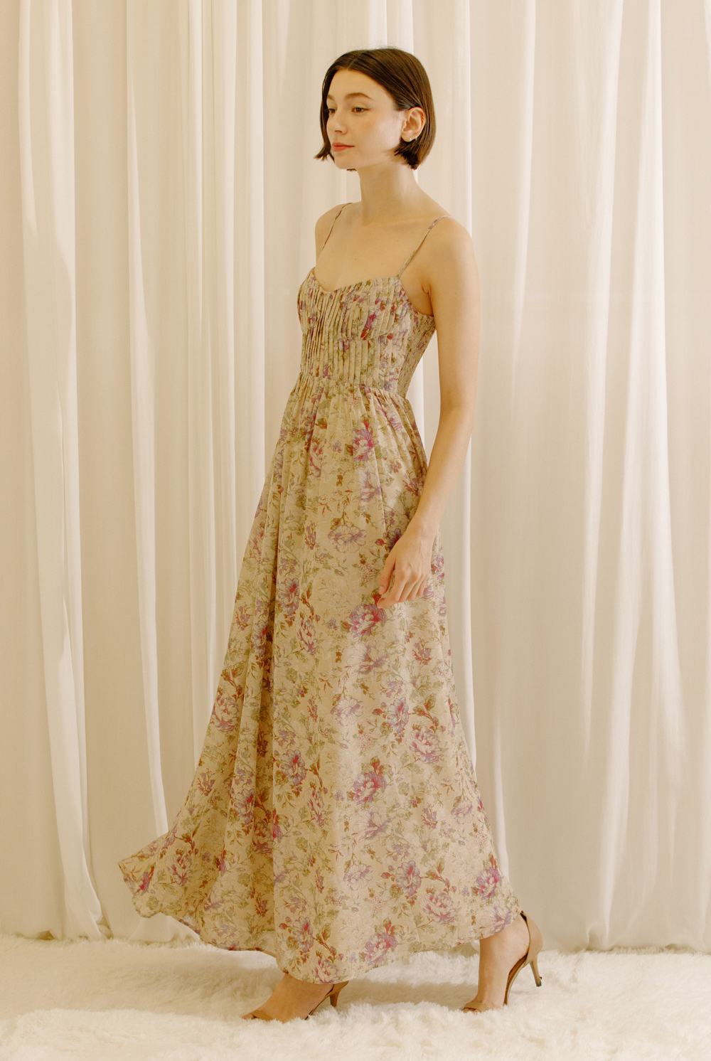 Side view of a model wearing a maxi dress with a romantic floral print and a flowy maxi silhouette.