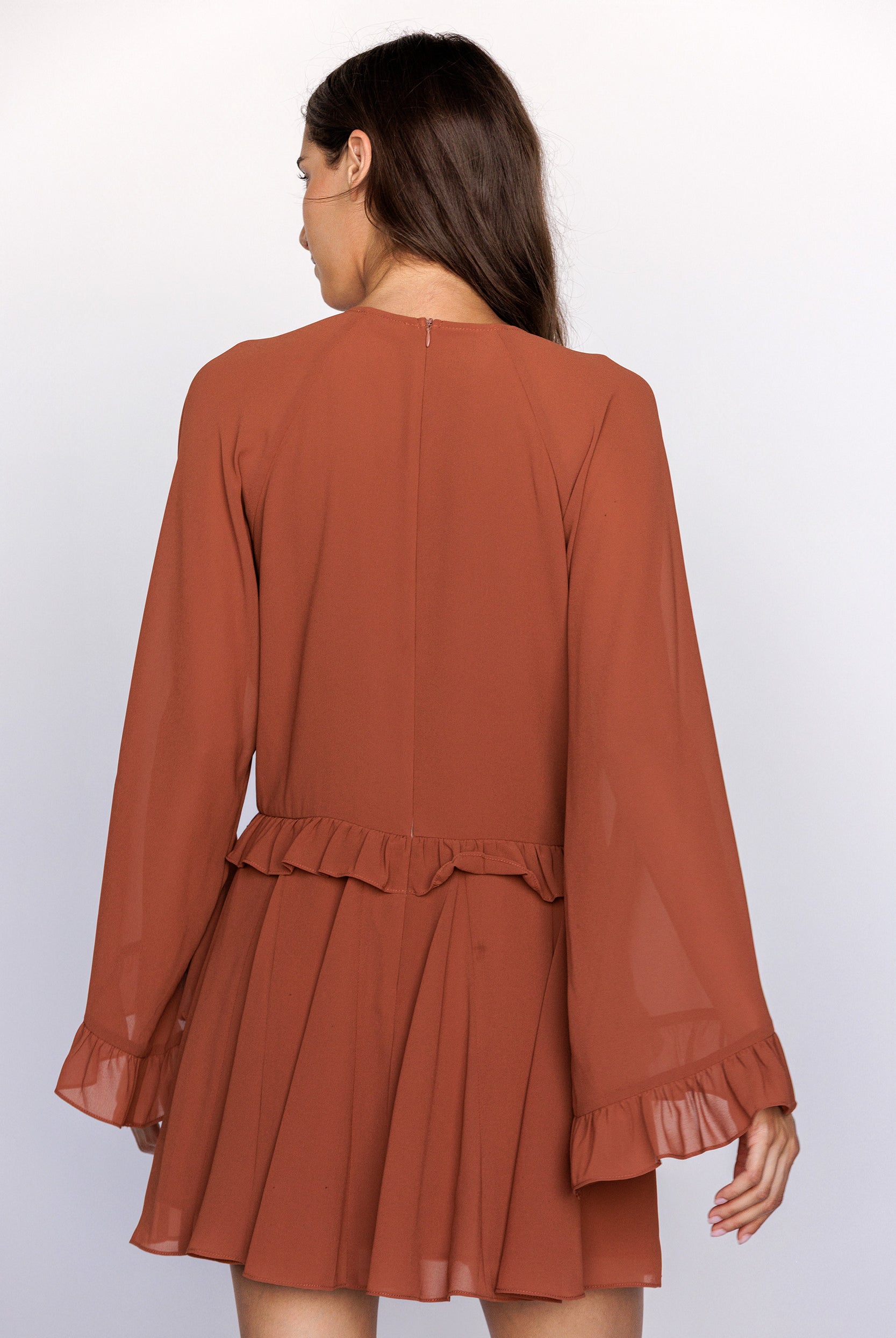 Brown dress with long sleeves and ruffled layers on a white background