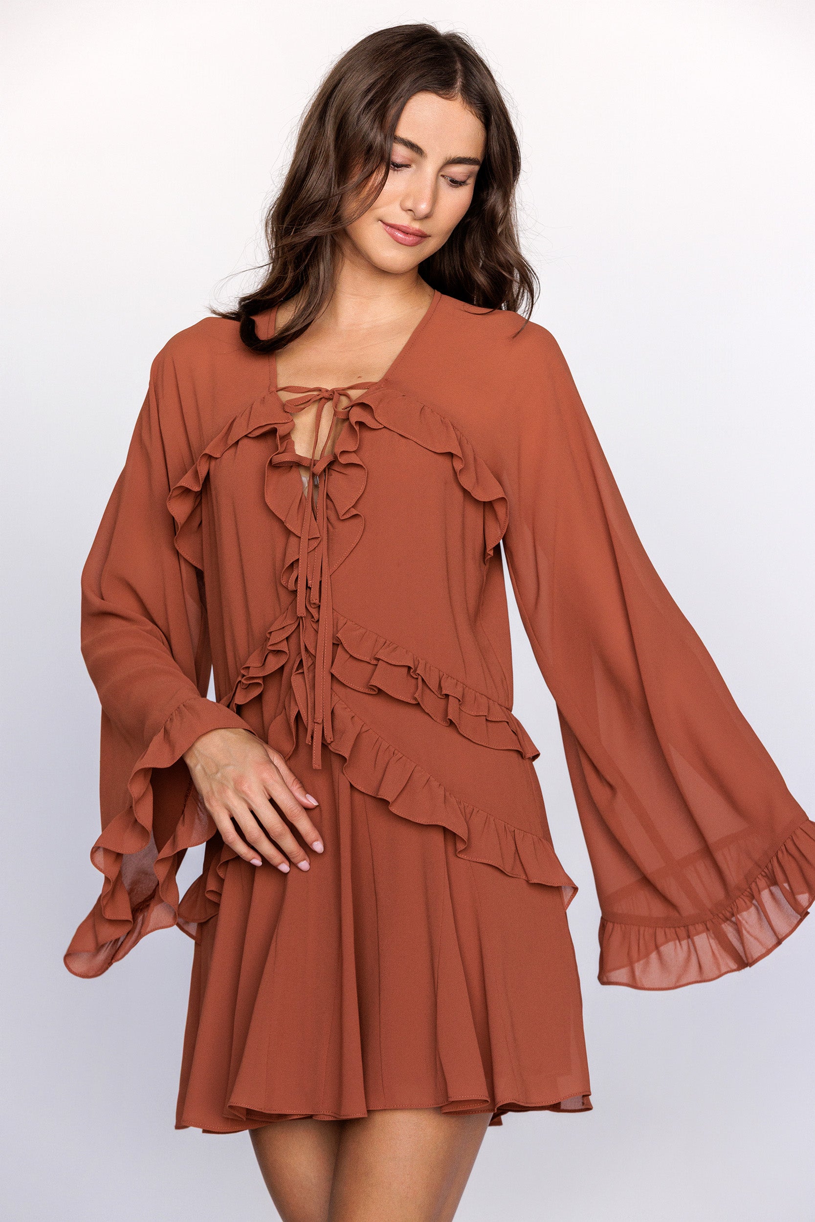 Woman wearing a rust-colored dress with ruffled details on a white background