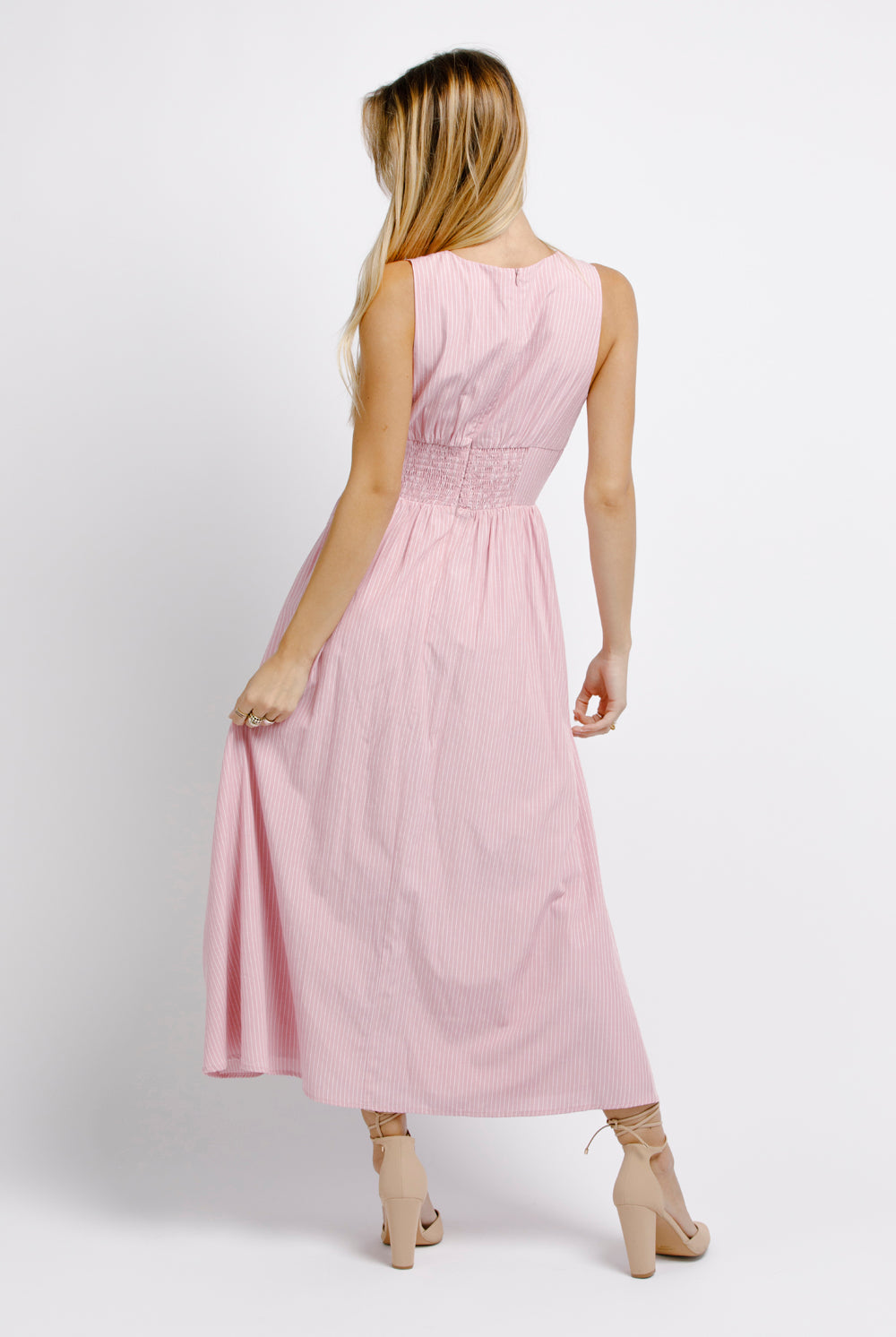 Back view of a woman wearing a pink midi dress on a white background