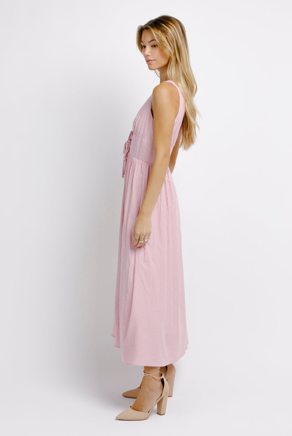 Side view of a woman wearing a pink midi dress on a white background