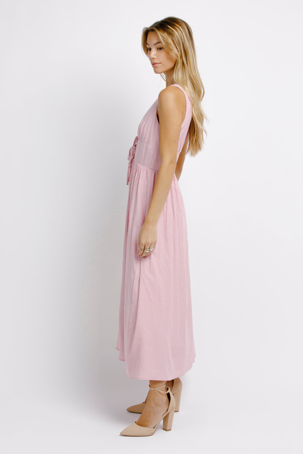 Side view of a woman wearing a pink midi dress on a white background